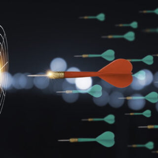 Closeup of Red dart among green arrow darts shooting to one target board . It is symbol of business investment competition to achieve goal and target.